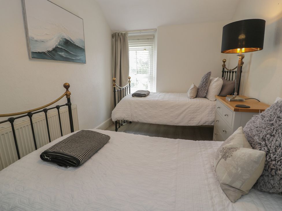 A bedroom with two beds and a nightstand at The Hideaway in Penrhyn Bay