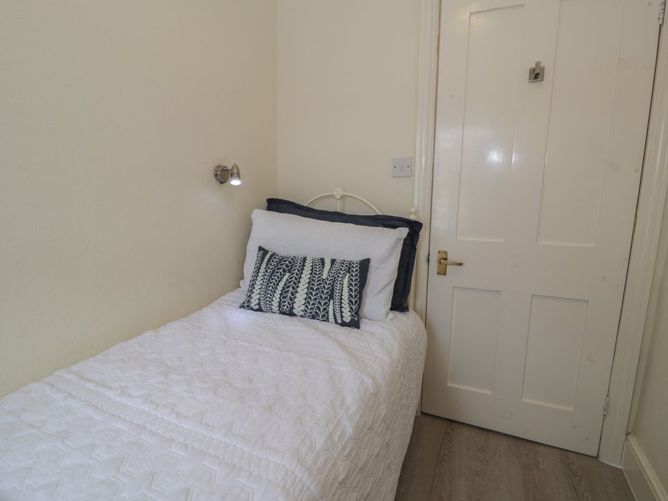 A bedroom with a bed and wall light at The Hideaway in Penrhyn Bay