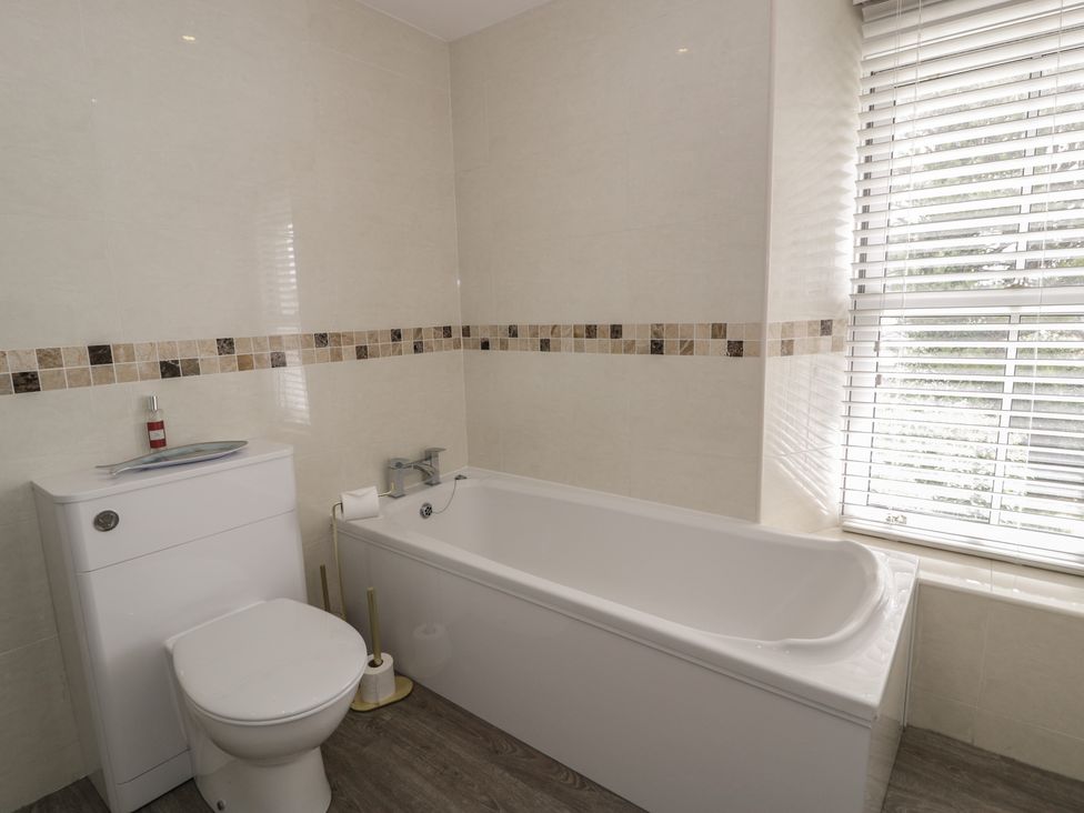 A bathroom with a bathtub, toilet, and sink at The Hideaway Penrhyn Bay