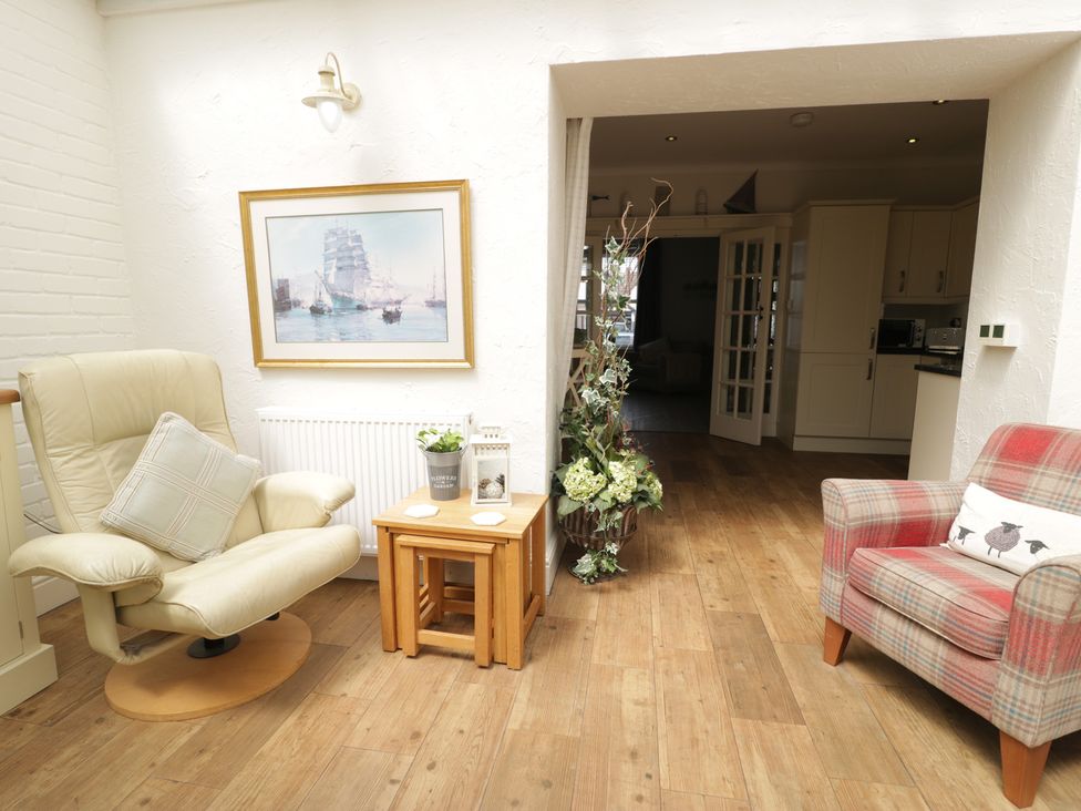 A conservatory with a chair and table at The Hideaway in Penrhyn Bay