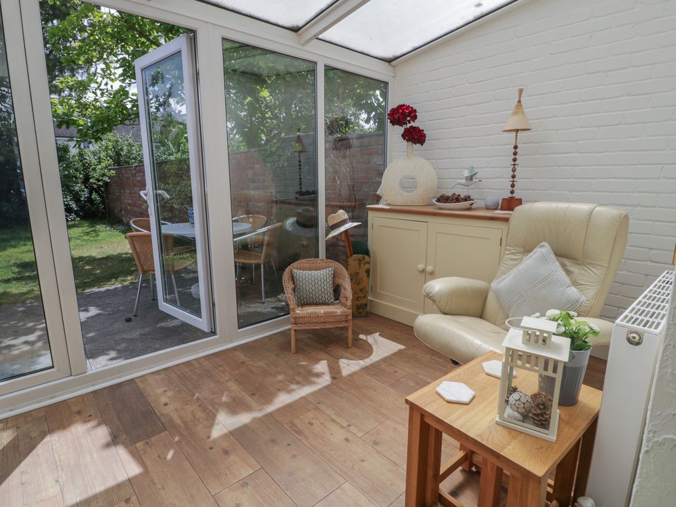 A conservatory with a chair and table at The Hideaway in Penrhyn Bay