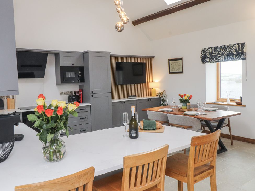 A kitchen with a dining area and kitchen appliances at 2 Trem Y Mor Llanfwrog near Llanfachraeth