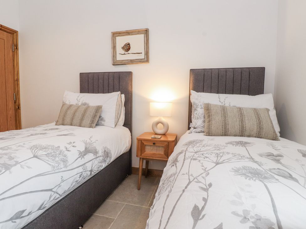 A bedroom with two beds and a nightstand at 2 Trem Y Mor Llanfwrog near Llanfachraeth