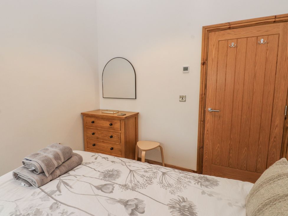 A bedroom with a bed and wooden furniture at 2 Trem Y Mor Llanfwrog near Llanfachraeth
