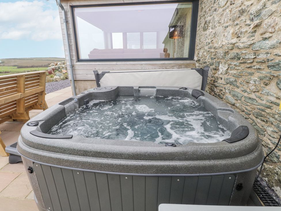 A hot tub next to a wooden bench at 2 Trem Y Mor Llanfwrog near Llanfachraeth