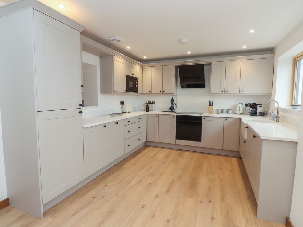 A kitchen with cabinets, appliances, and a sink at Hen Penmynydd in Llanfwrog near Llanfachraeth