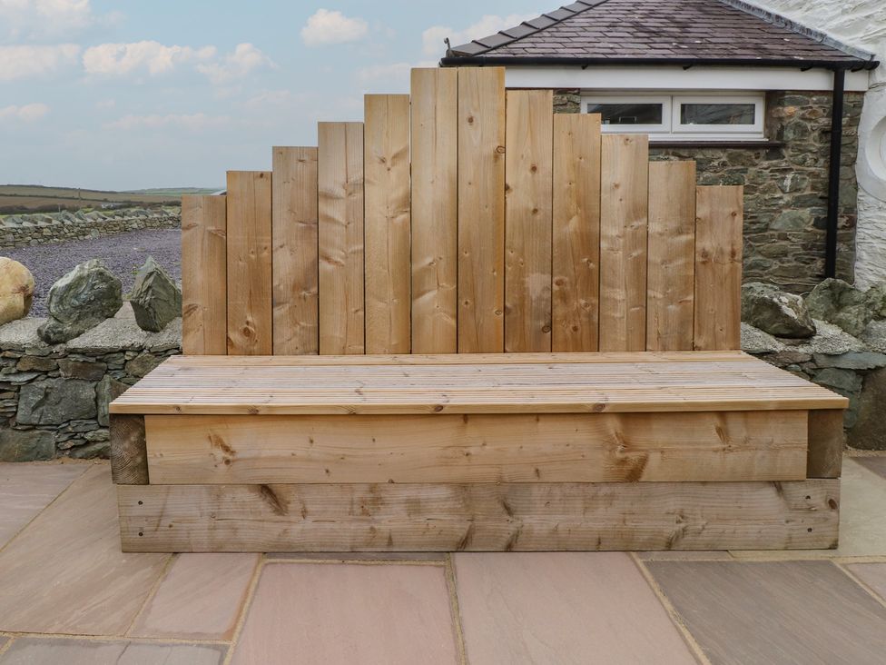 A wooden bench against a stone wall at Hen Penmynydd Llanfwrog near Llanfachraeth