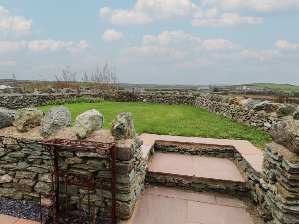 A garden with a stone wall and steps at Hen Penmynydd in Llanfwrog near Llanfachraeth