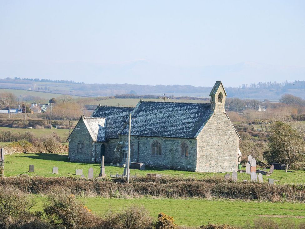 A church with gravestones in a field at Hen Penmynydd in Llanfwrog near Llanfachraeth