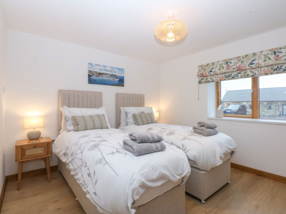 A bedroom with two beds and a nightstand at Hen Penmynydd Llanfwrog near Llanfachraeth