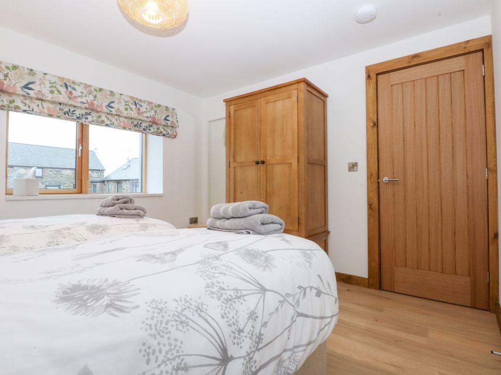A bedroom with two beds and a wardrobe at Hen Penmynydd Llanfwrog near Llanfachraeth