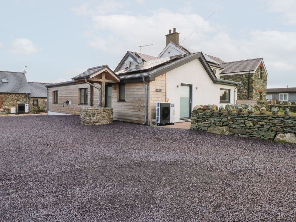 A house with a stone wall and gravel driveway at Hen Penmynydd near Llanfachraeth