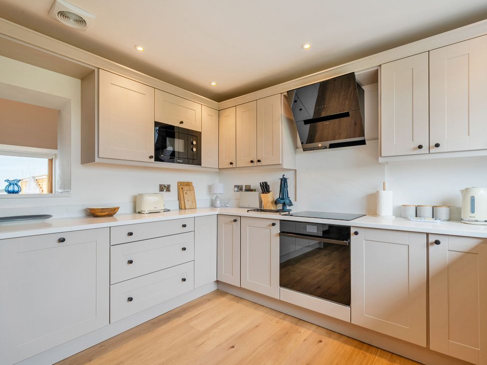 A kitchen with cabinets, microwave, and cooking appliances at Hen Penmynydd Llanfwrog near Llanfachraeth