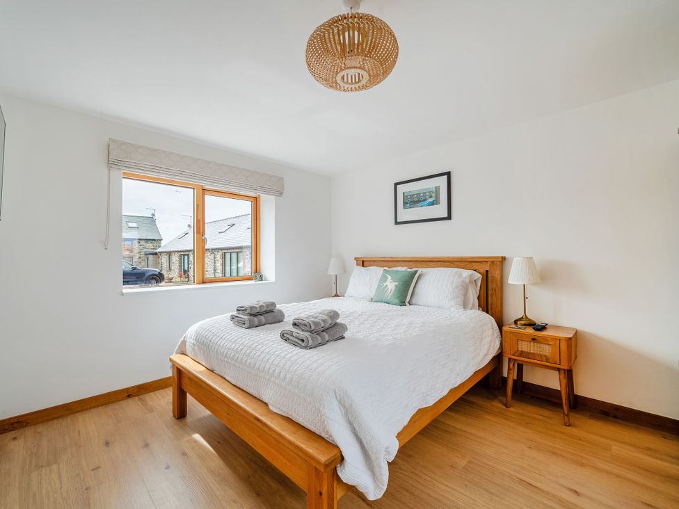 A bedroom with a bed and bedside table at Hen Penmynydd in Llanfwrog near Llanfachraeth