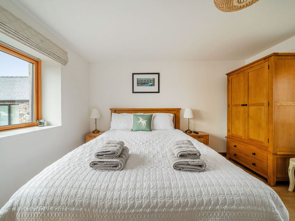 A bedroom with a bed and wardrobe at Hen Penmynydd Llanfwrog near Llanfachraeth