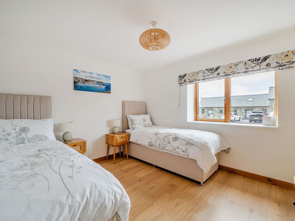 A bedroom with two beds and a window at Hen Penmynydd in Llanfwrog near Llanfachraeth