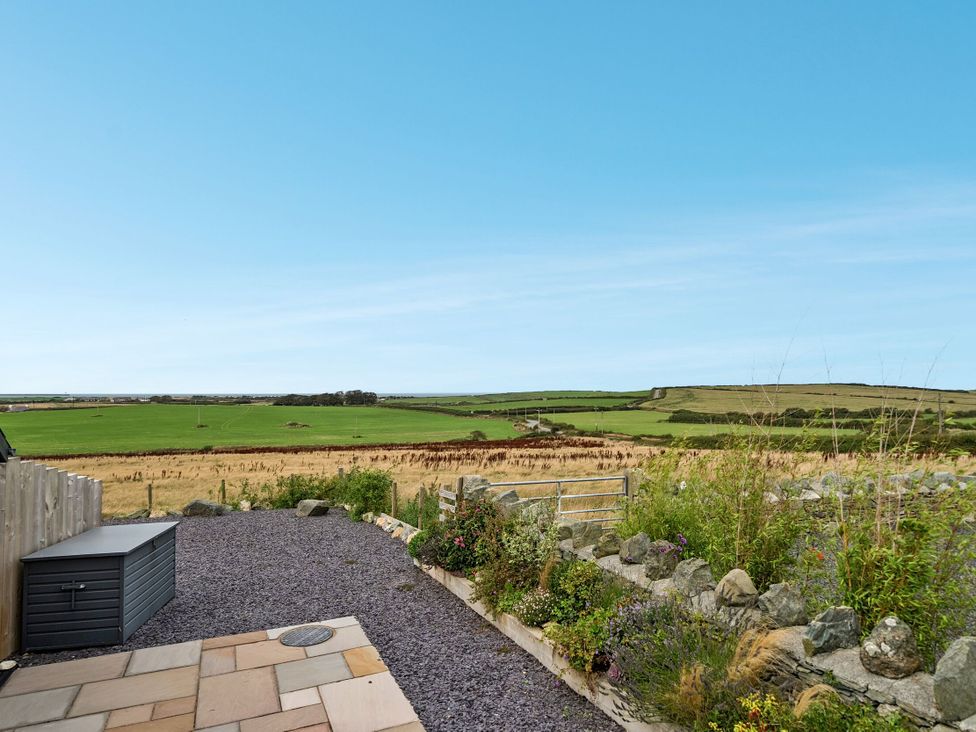 A garden view with fields and a blue sky at Hen Penmynydd in Llanfwrog near Llanfachraeth