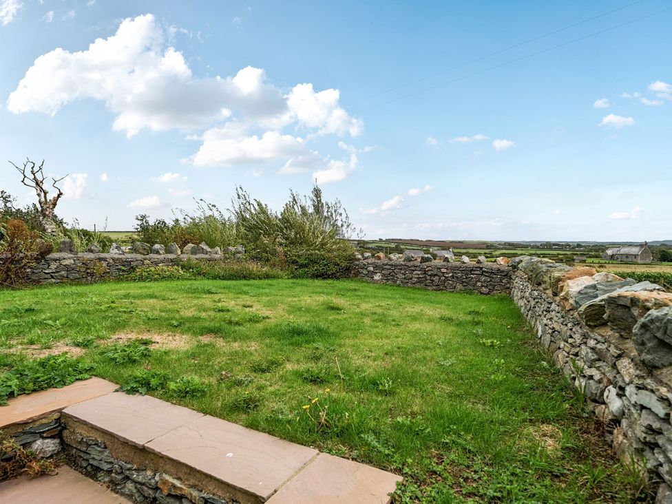 A garden area with grass and stone walls at Hen Penmynydd in Llanfwrog near Llanfachraeth