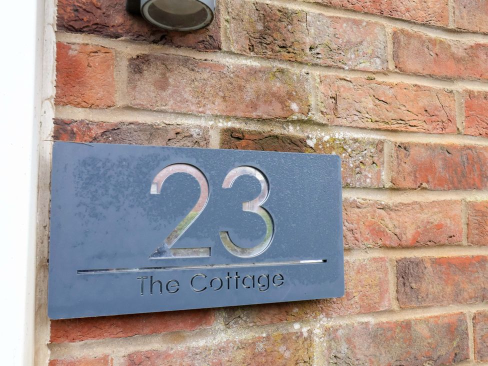 A house number sign on a brick wall at The Cottage