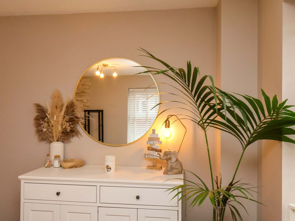 A room with a mirror and table decorated with a lamp and plants at 23 Main Street
