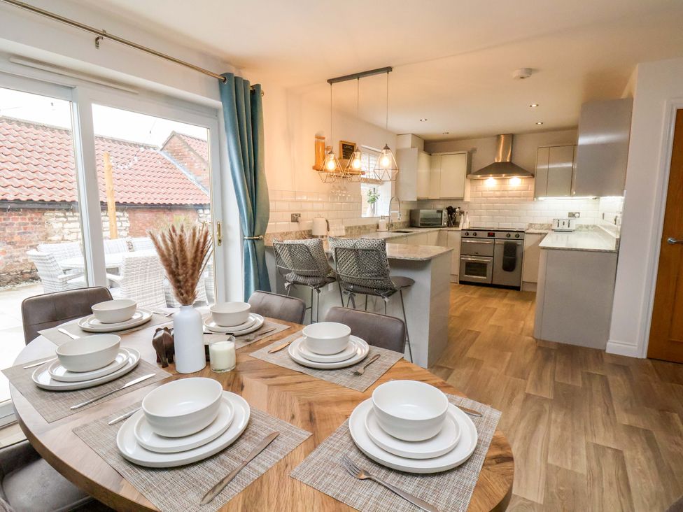 A dining area with a table set for meals and an open kitchen at 23 Main Street 