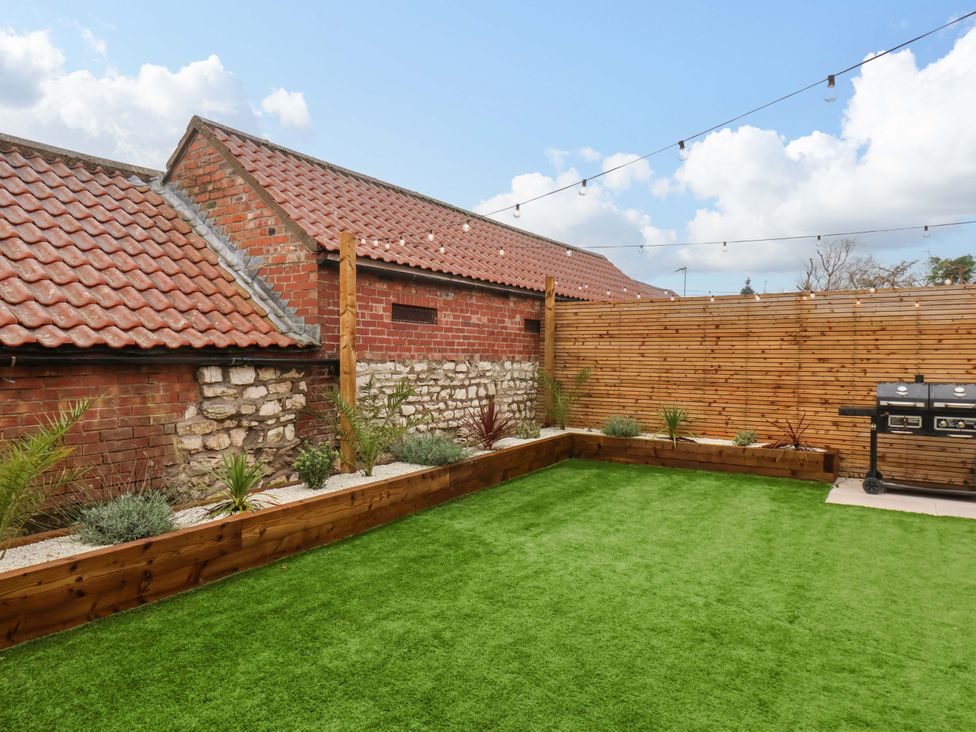 A garden with grass, plants, and a grill at 23 Main Street