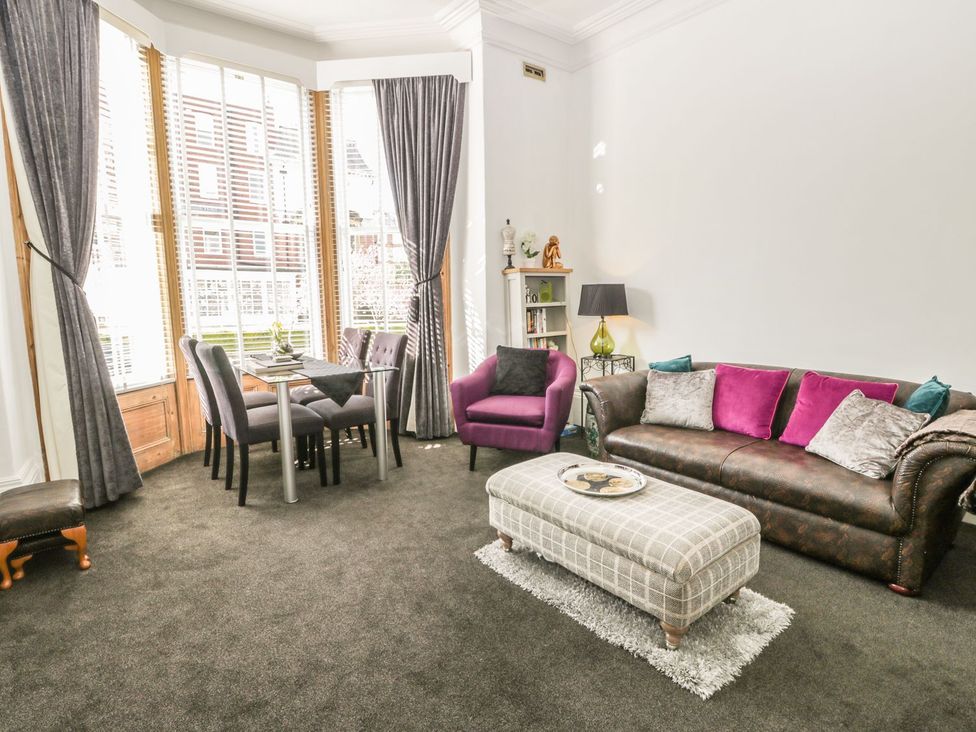 A living room with a sofa, dining table and chairs at Esplanade Gardens, Apartment 1 Scarborough