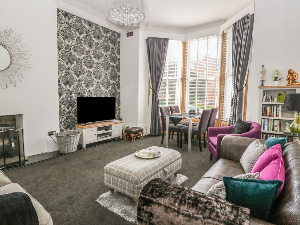 A living room with a TV, sofa and dining area at Esplanade Gardens, Apartment 1, Scarborough