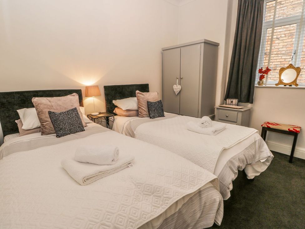A bedroom with two beds, a wardrobe, and a nightstand at Esplanade Gardens, Apartment 1 in Scarborough