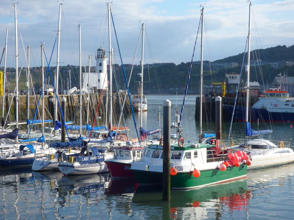 A collection of boats with a lighthouse in the background at Esplanade Gardens, Apartment 1 Scarborough