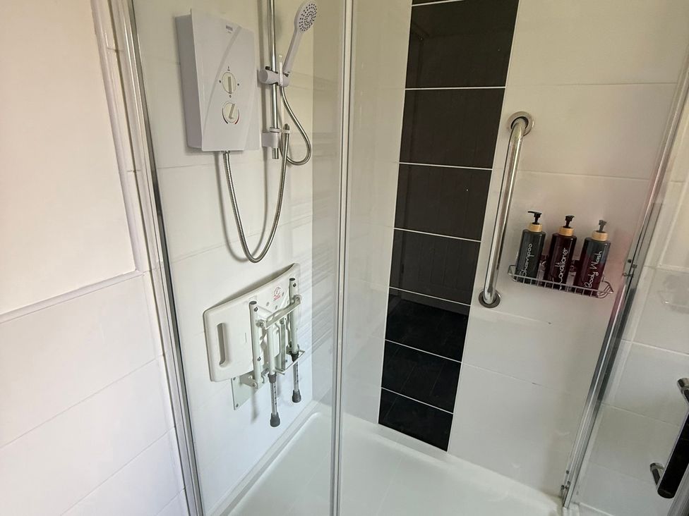 A shower with a grab bar and soap dispenser at Beach Side Bungalow