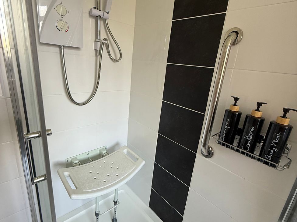 A shower with a chair and body wash products at Beach Side Bungalow