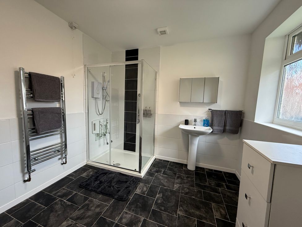 A bathroom with a shower, sink, and towels at Beach Side Bungalow