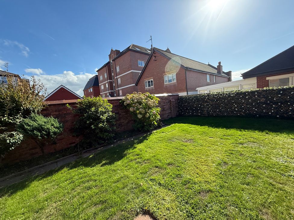 A garden with grass and flower bushes at Beach Side Bungalow