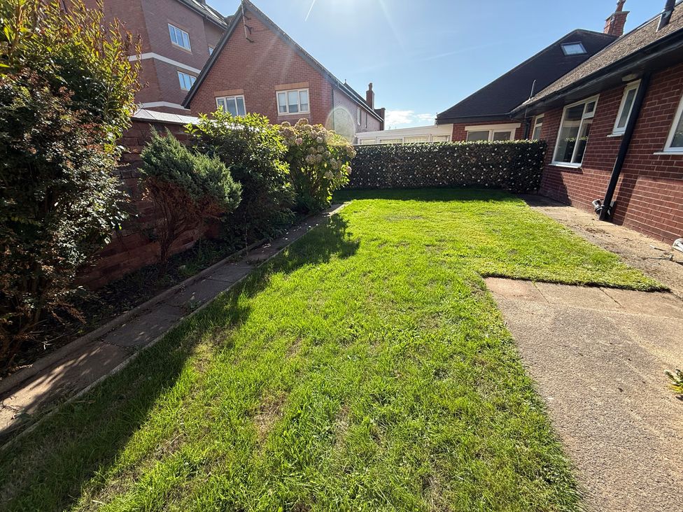 A garden with grass and paved path at Beach Side Bungalow