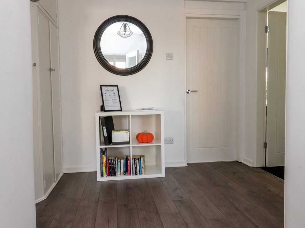 A hallway with a shelf displaying books and a pumpkin at Beach Side Bungalow in Lytham St. Annes