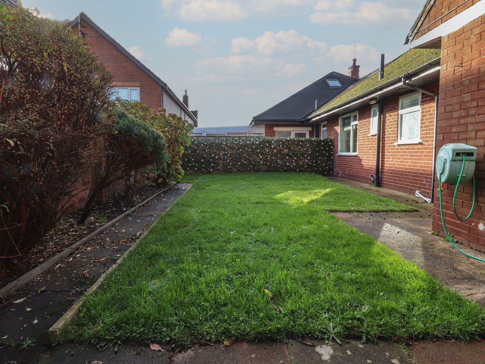 A garden with grass and a wall at Beach Side Bungalow in Lytham St. Annes