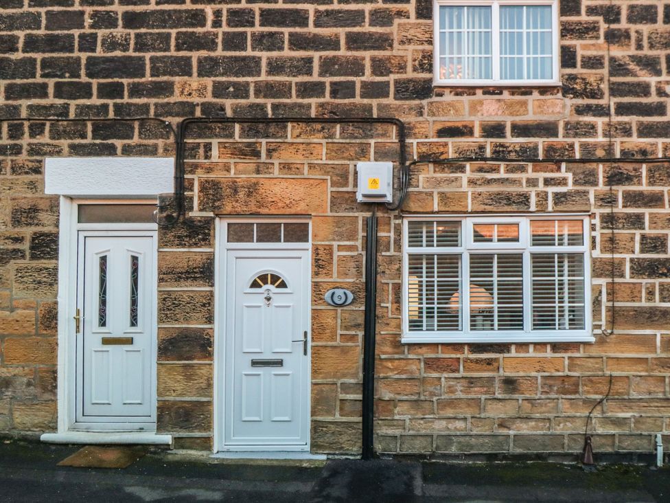A white door and window on a stone wall at Cliffe Cottage in Brotton, North Yorkshire