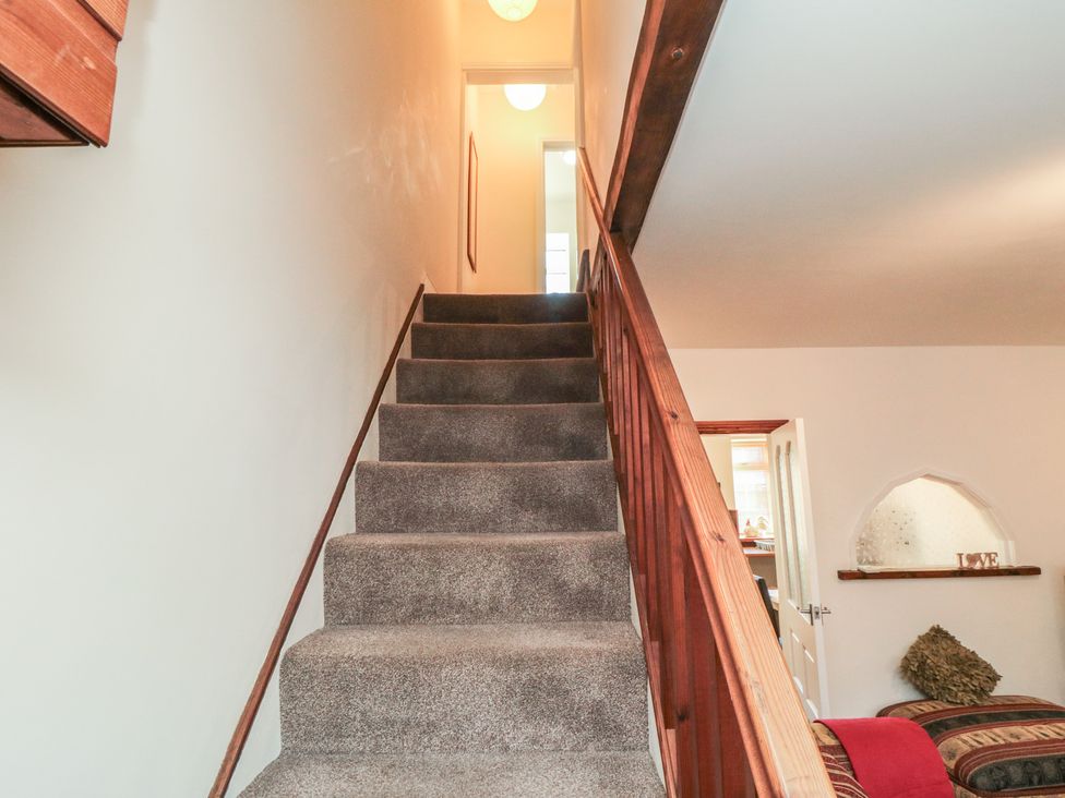 A staircase with a railing leading to a door at Cliffe Cottage, Brotton, North Yorkshire