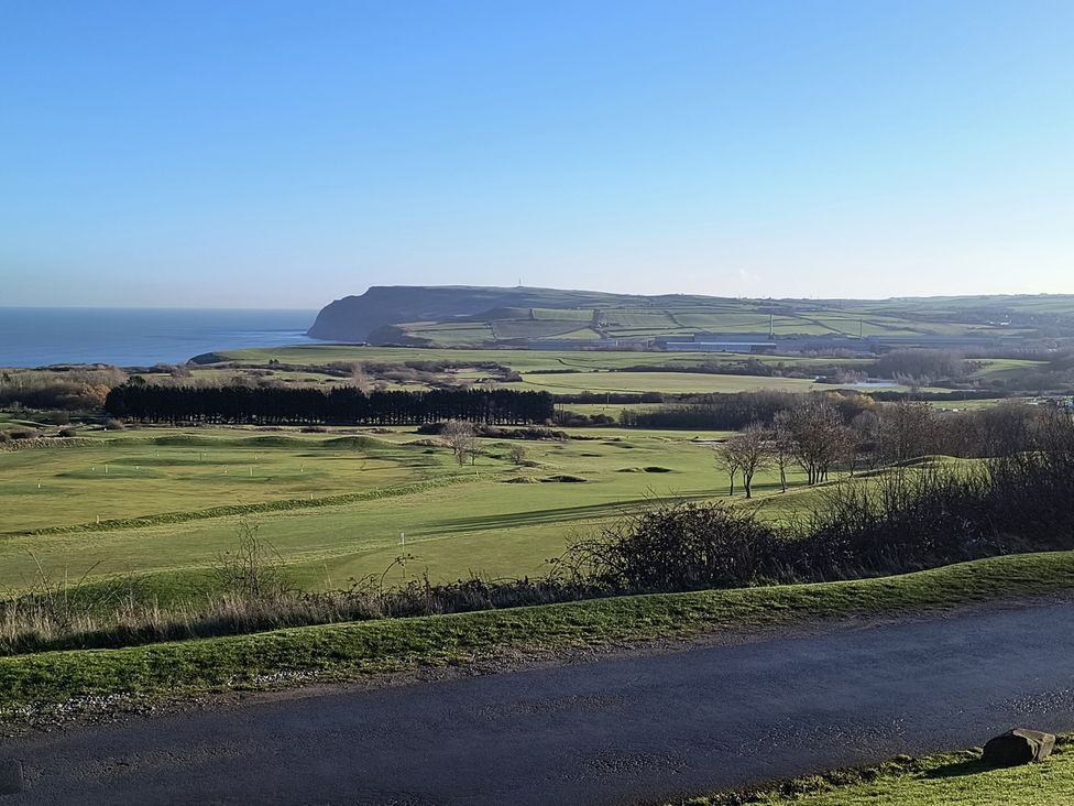A view of a golf course with hills and the sea at Cliffe Cottage, Brotton, North Yorkshire