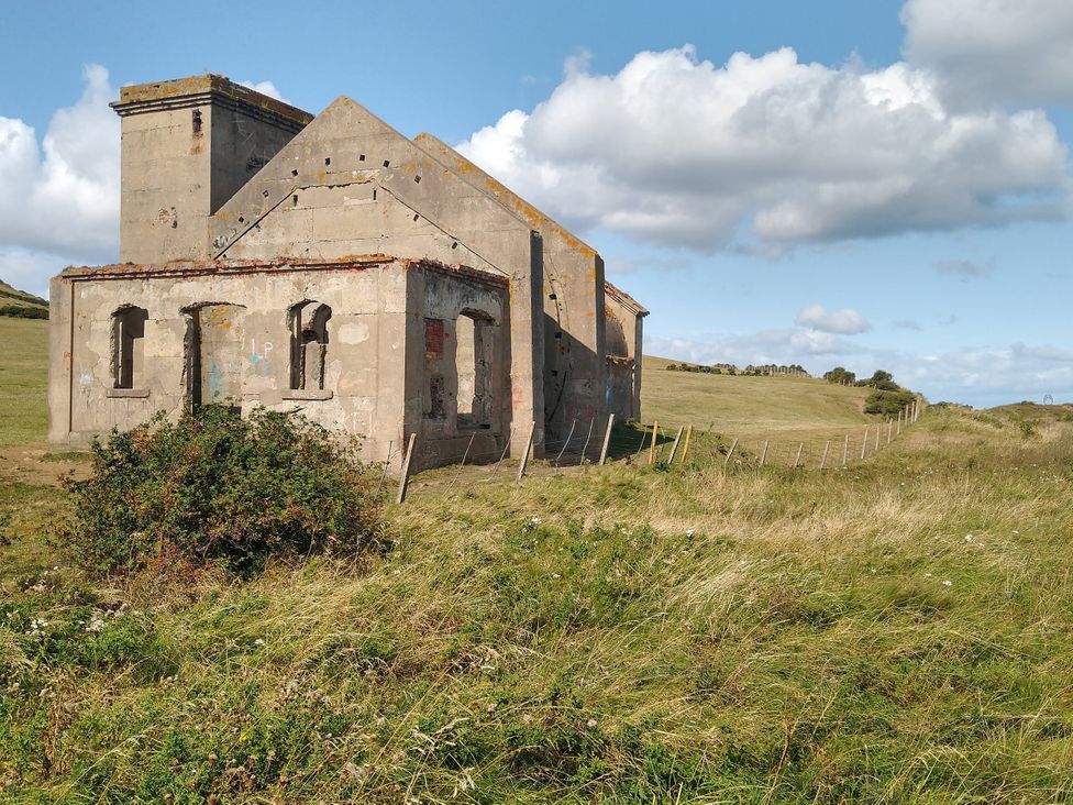 An abandoned building on a hillside with grass and a fence at Cliffe Cottage Brotton, North Yorkshire