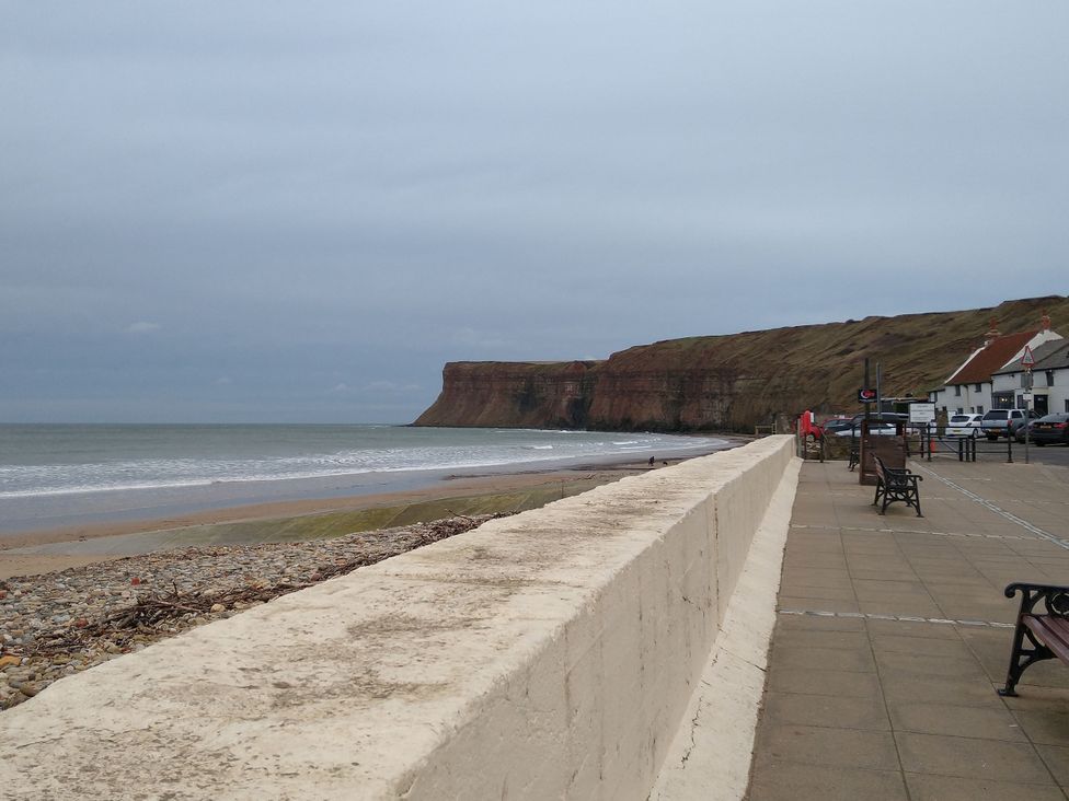 A beach with a cliff and benches at Cliffe Cottage Brotton North Yorkshire