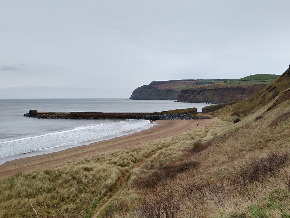 A beach area with sand and a pier along the sea at Cliffe Cottage Brotton, North Yorkshire