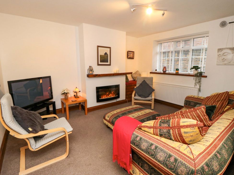 A living room with a television, sofa and fireplace at Cliffe Cottage, Brotton, North Yorkshire