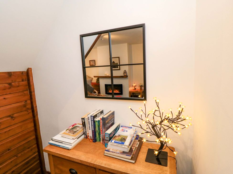 A living room with a mirror and books on a table at Cliffe Cottage in Brotton, North Yorkshire