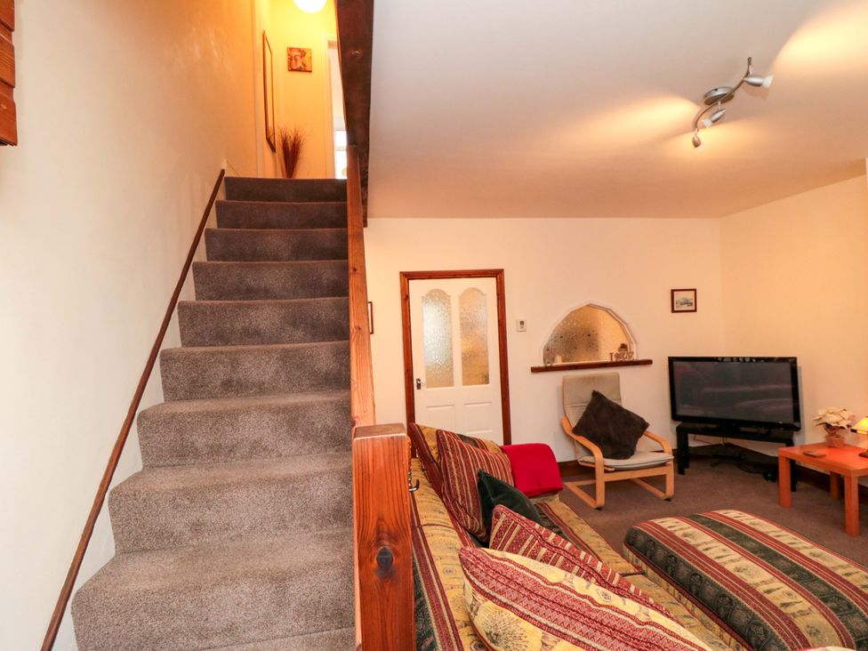 A living room with stairs and a television at Cliffe Cottage in Brotton, North Yorkshire