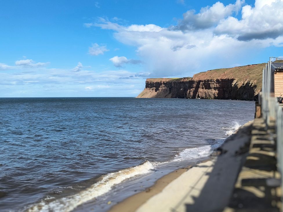 A beach with cliffs and water at Cliffe Cottage in Brotton, North Yorkshire