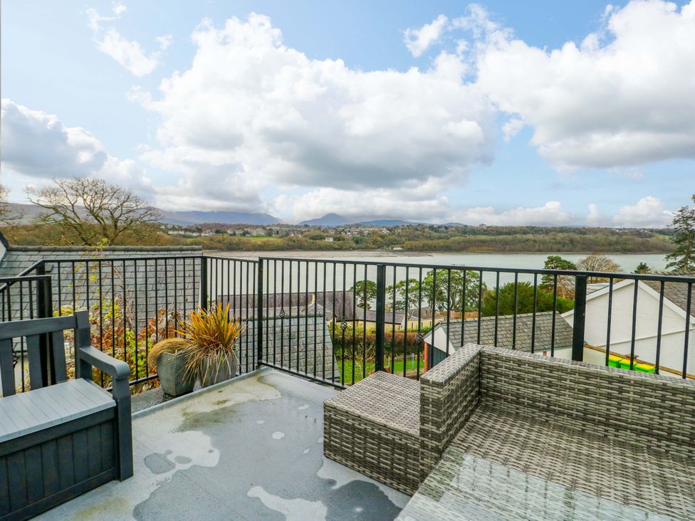 A balcony with rattan furniture overlooking a river at 4 Brynteg Terrace Menai Bridge