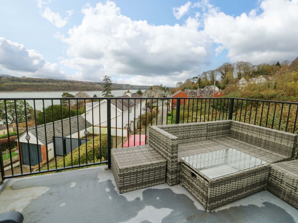 A balcony with rattan furniture and a water view at 4 Brynteg Terrace in Menai Bridge