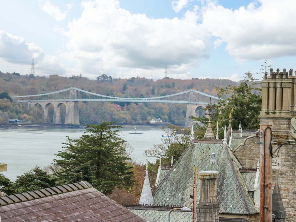 A view of a bridge over water and buildings in Menai Bridge